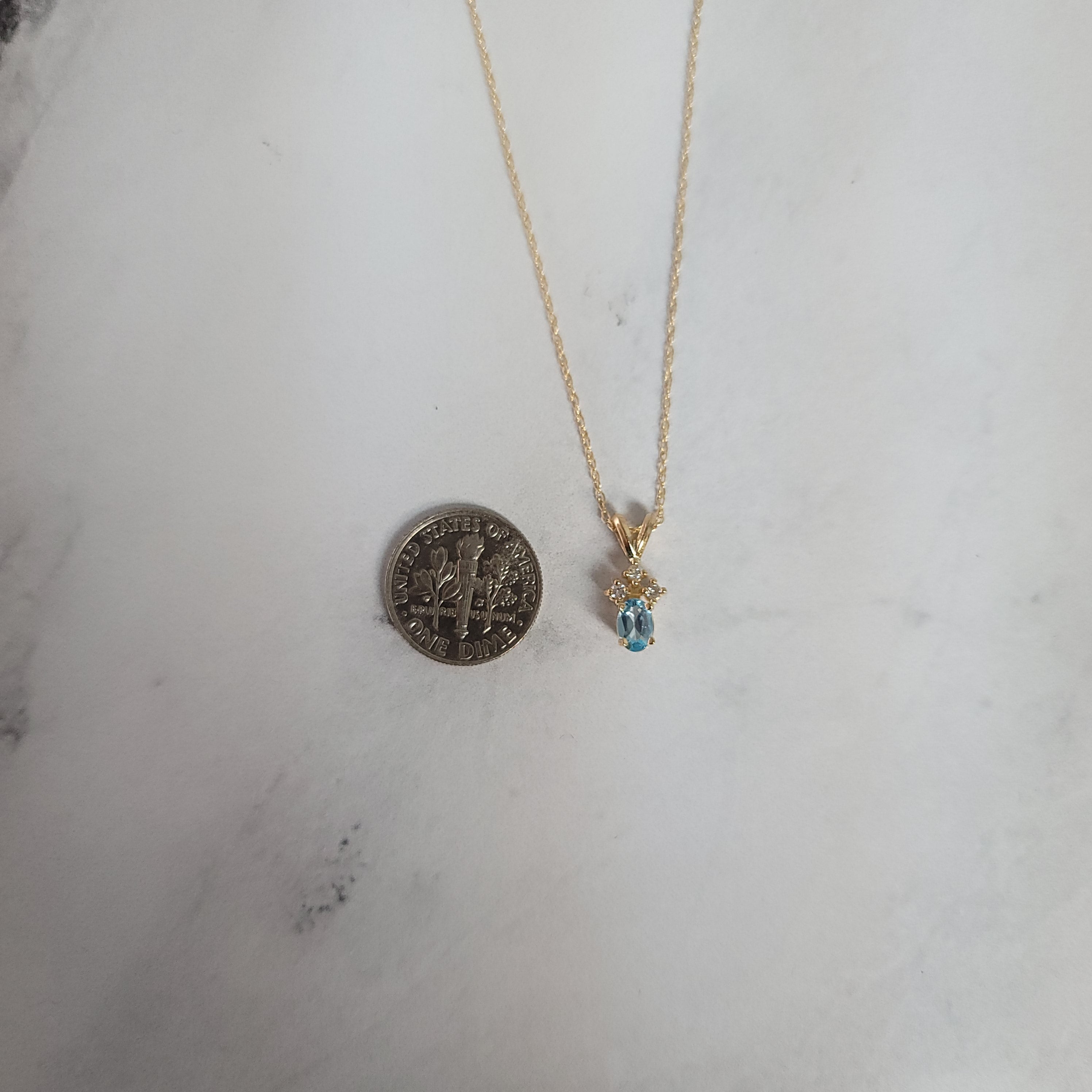 Collar con topacio azul ovalado y tres diamantes pequeños en oro amarillo de 14 k