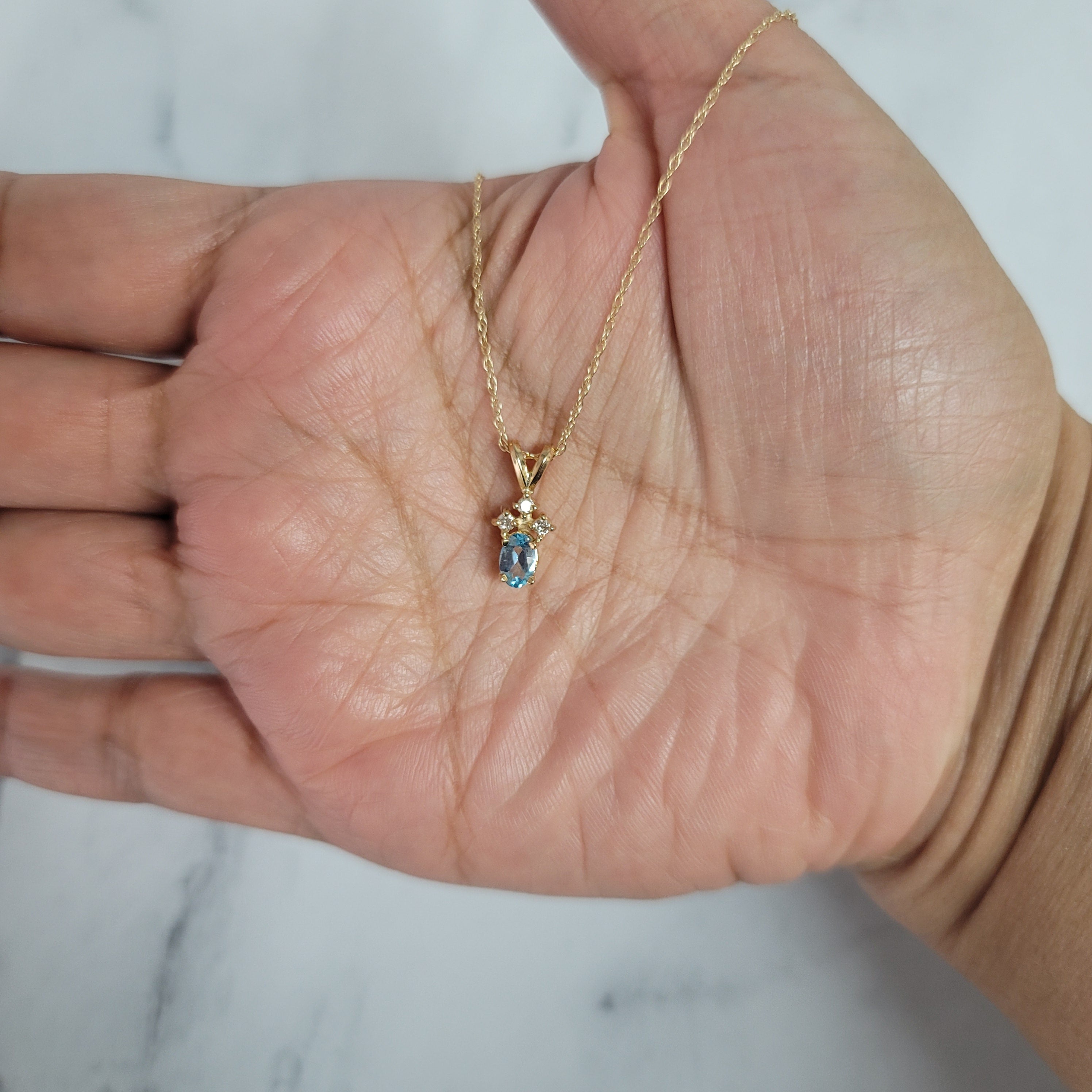 Collar con topacio azul ovalado y tres diamantes pequeños en oro amarillo de 14 k